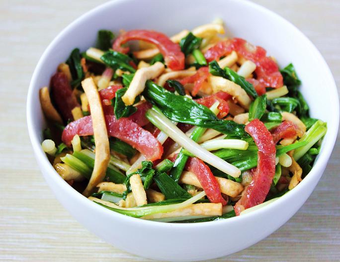 Although ramps are rarely used in Chinese cooking, they work wonderfully with garlic chives (韭菜), pressed tofu, and Chinese sausages (lap cheong) in this stir-fry that tastes at once Chinese and American.