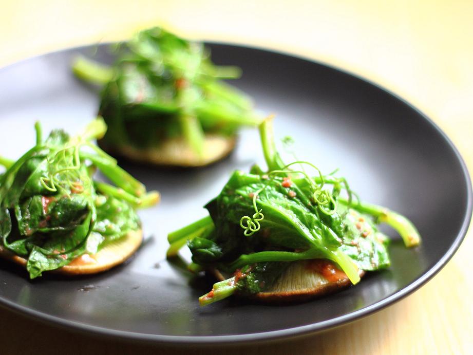 Pea shoots are the immature tips of young pea plants, which include leaves, tendrils, and stems—all deliciously tender and crisp with a fresh pea flavor. Here, they are mixed with garlic and fermented tofu and steamed briefly atop shiitake mushroom caps.
