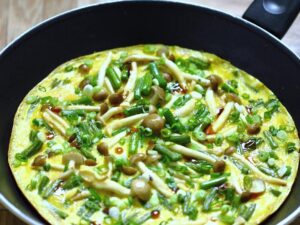 In many countries, garlic scapes are highly prized for their mild garlic flavor and tender-crisp texture. They work wonderfully with beech mushrooms in this omelet.