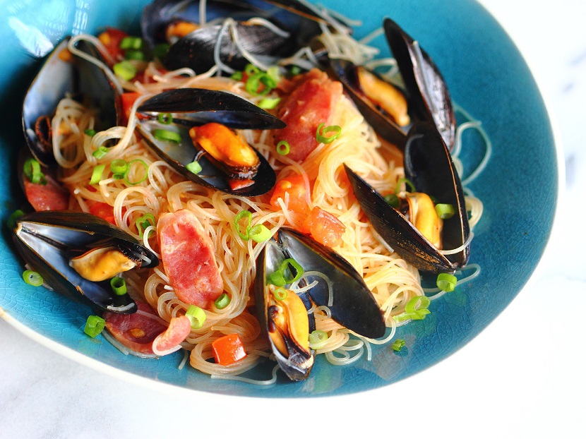 There are many exciting ways to cook mussels, beyond the familiar French-style steamed mussels. Here, mussels, Chinese sausage, rice noodles, and tomatoes create a simple and exciting one-dish meal.
